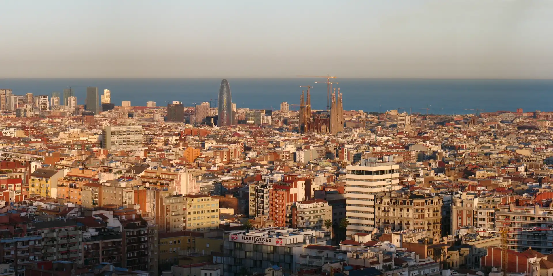 Barcelona al atardecer desde el parque del Putxet, con la Sagrada Família y la torre Glòries frente al mar