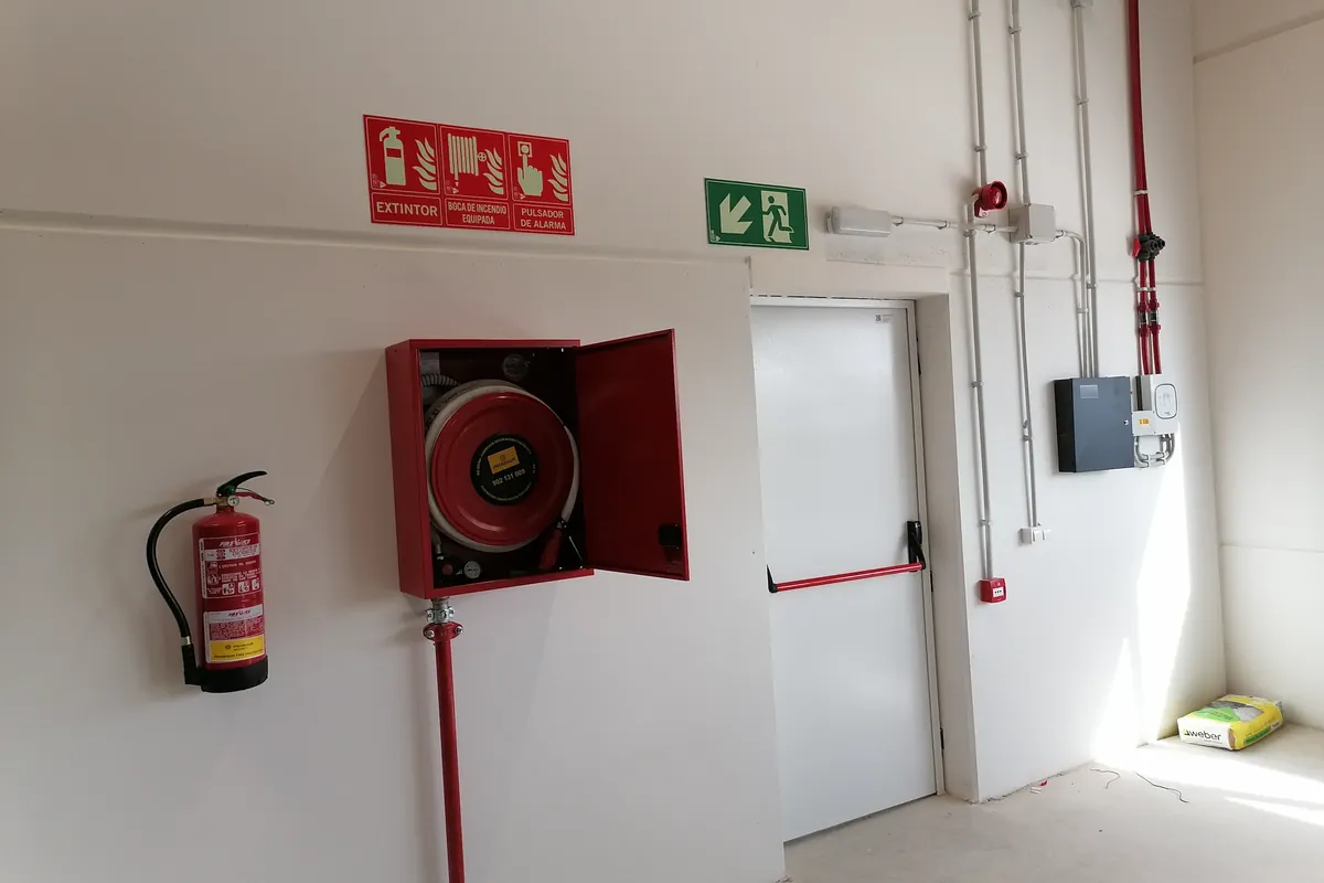 Passadís d’un edifici amb una boca d’incendi equipada i un extintor senyalitzats a la paret